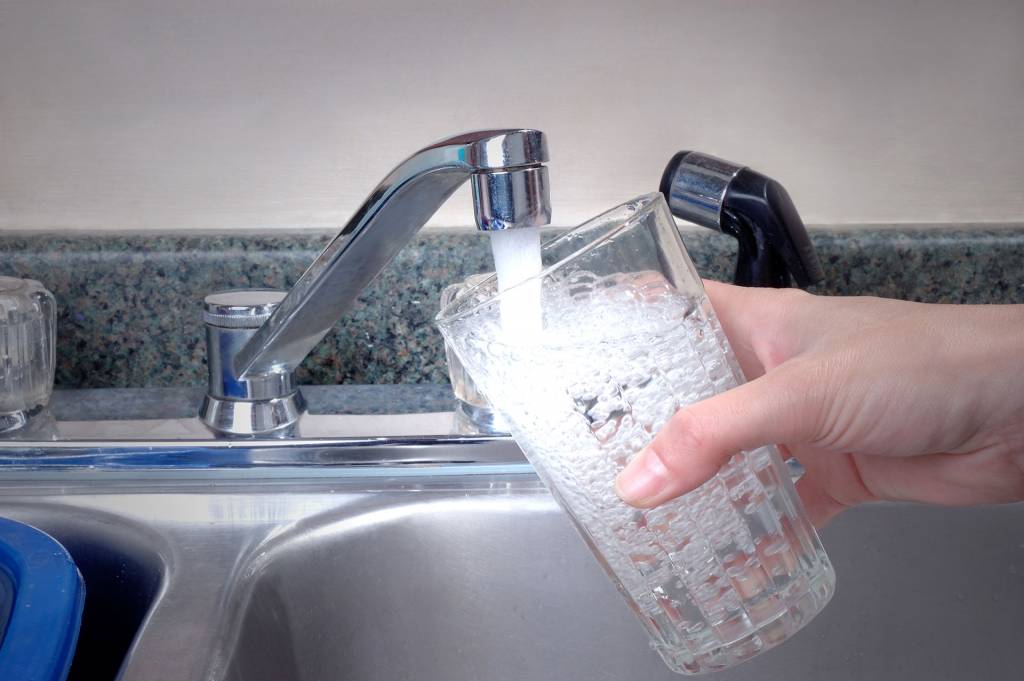 Juomavettä otetaan hanasta lasiin.