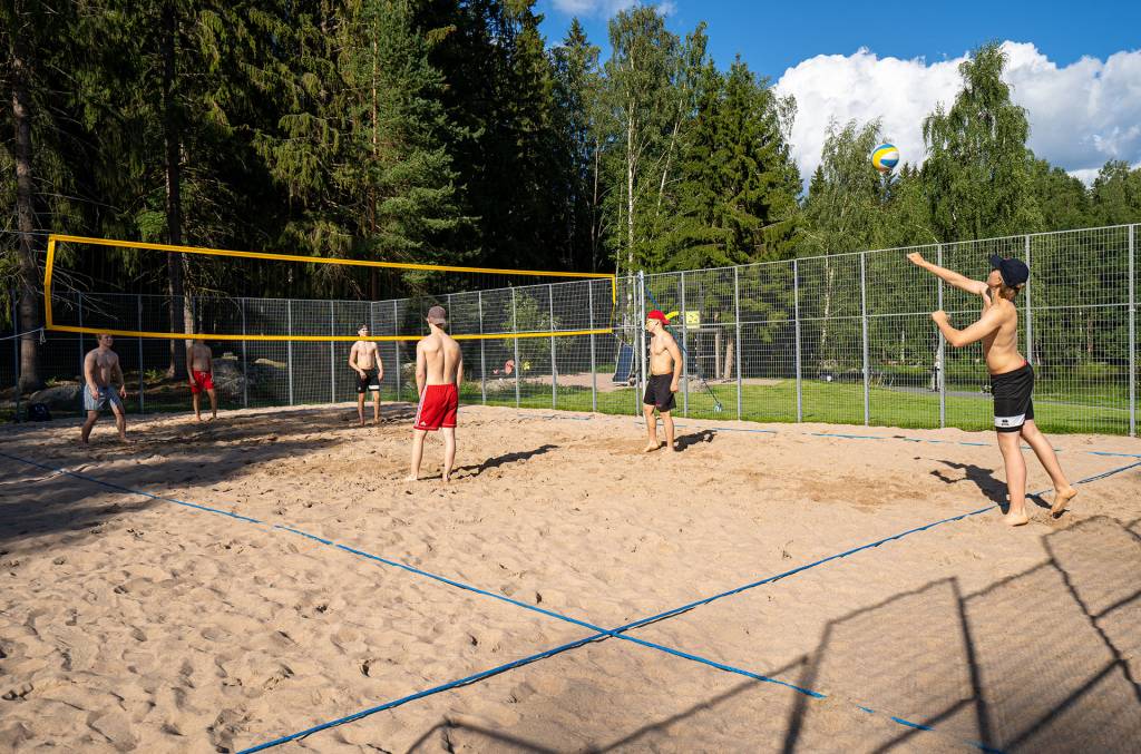 Miehet pelaavat beach volleyta kesällä.