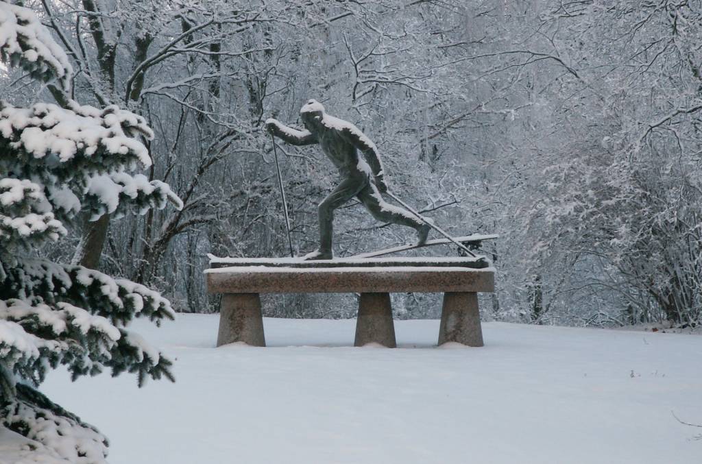 Hiihtäjä-patsas talvella lumisessa maisemassa Lepänkorvan puistossa Valkeakoskella.