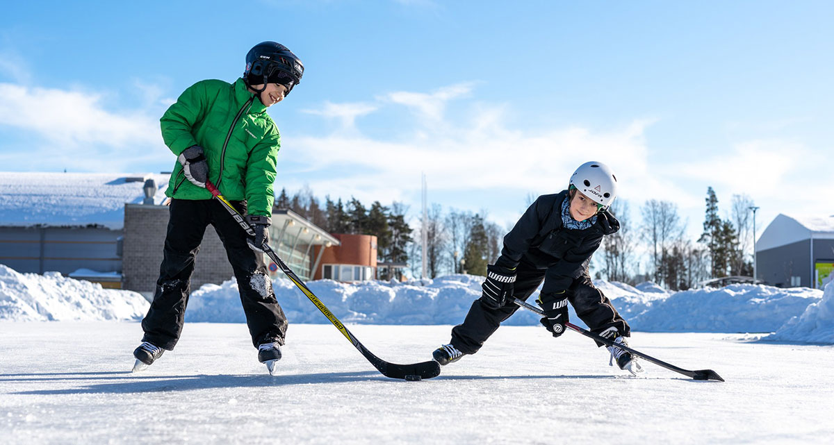 Kaksi poikaa mailojen kanssa luistelemassa.