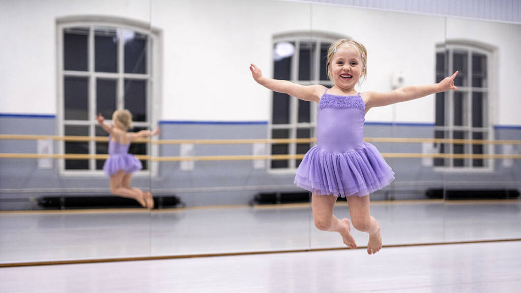Lapsi balettipuvussaan hyppää ilmaan.
