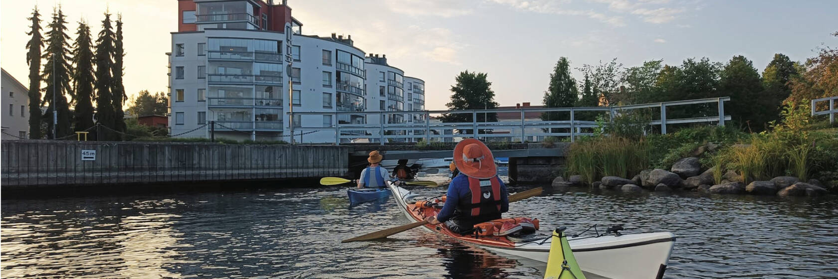 Melojat alittamassa keskustassa pikkusiltaa ilta-auringossa.