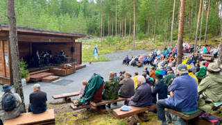 Yleisöä istuu Säres Centerin Metsäteatterissa ja katselee esiintyjiä lavalla.