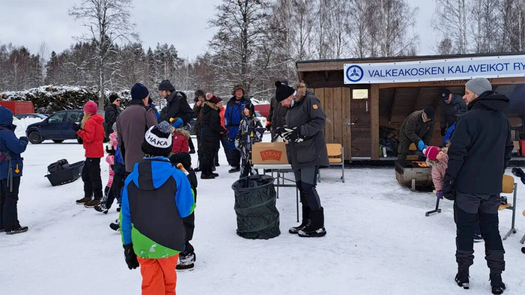 Ihmisiä laavun edessä Lotilan järven rannalla.